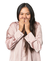 Young chinese woman isolated laughing about something, covering mouth with hands.