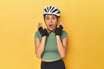 Cyclist middle aged woman with helmet and gloves posed surprised and shocked.