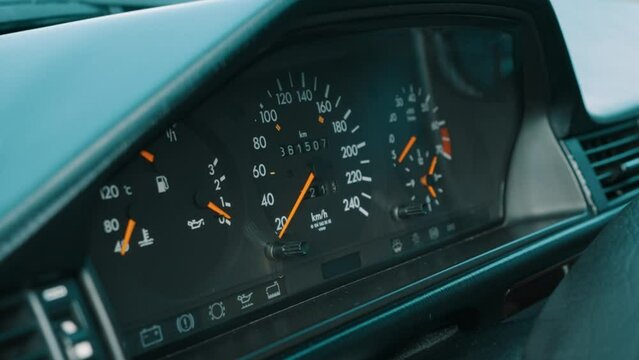 Car dashboard gauges, speedometer, tachometer, fuel gauge, temperature indicator, vehicle odometer showing mileage, illuminated dials, close-up, vehicle interior, indication of car status, measurement