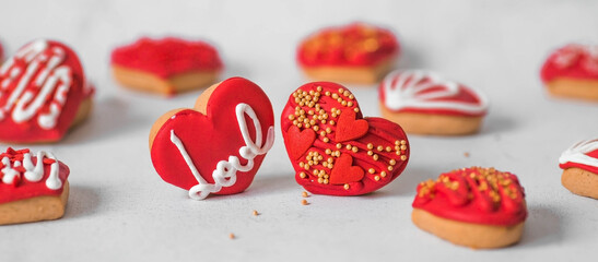 Homemade ginger cookies in the shape of a heart in red icing sugar. Delicious ginger cookies heart on a light concrete background. Freshly baked gingerbread cookies for Valentine's Day.