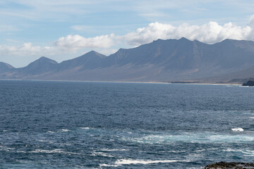 View on difficult to access golden sandy long Cofete beach hidden behind mountain range on Fuerteventura, Canary islands, Spain