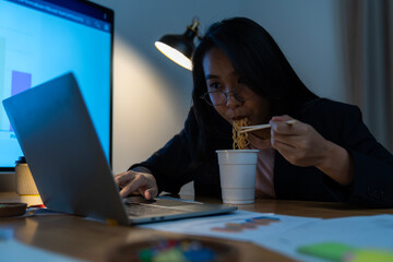 A female office worker working late and eating instant noodles alone in the office