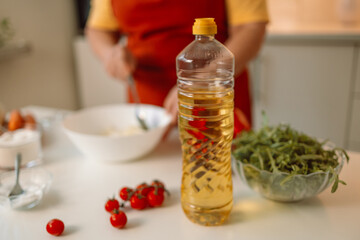 Woman seasons a vegetable salad while preparing food in the kitchen. Unrecognizable chef adds olive oil while preparing a vegetarian meal at home. Healthy eating concept. 