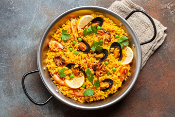 Traditional spanish seafood paella with rice, mussels, shrimps in a pan on wooden background. Top view. Flat lay