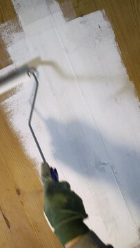 Painting the wooden surface white with a paint roller. DIY repair, repair by oneself and home improvement