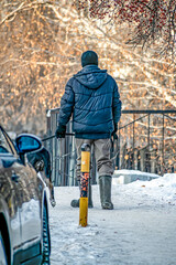 A man walks with a dog on the sidewalk on a winter day