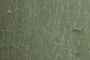 Green peeling paint on the wall. Old concrete wall with cracked flaking paint. Weathered rough painted surface with patterns of cracks and peeling. High resolution texture for background and design.