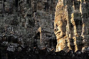 Giant face of the Bayon Angkor Wat temple illuminated by the morning sun