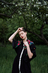 Slavic girl in a scarf near blooming apple trees