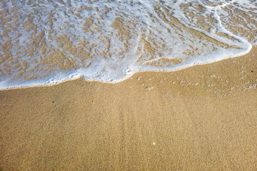 Fototapeta na wymiar Des bulles de l'ecume des vagues sur un sable blond d'une plage paradisiaque de vacances