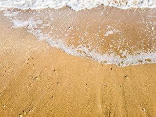 Fototapeta na wymiar Des bulles de l'ecume des vagues sur un sable blond d'une plage paradisiaque de vacances