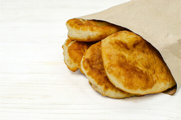 Pies in a paper bag on a white wooden background