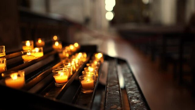 Burning candles on candleholders in the cathedral. Candles burning in row inside Catholic church for praying and spirituality. Concept of candlelight, sorrow, memory and religion.