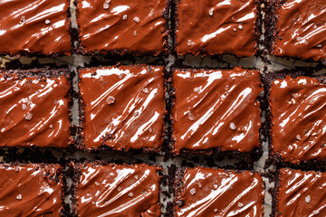 Cut square peaces of dark chocolate moist buttermilk sheet cake with chocolate butter cream, homemade dessert. - obrazy, fototapety, plakaty