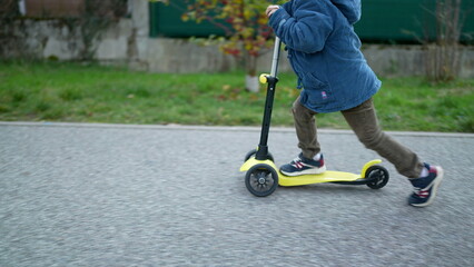 Obraz premium Active Three-Year-Old Boy Enjoying Ride on Three-Wheeled Scooter Outdoors