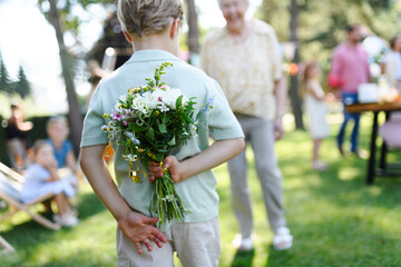 Beautiful senior birthday woman receiving flowers from grandchildren. Concept of garden birthday...