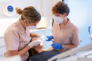 Dentist and assistant performing a filling on a tooth for a client in the modern dental clinic