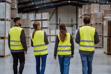 Obraz premium Rear view of warehouse workers walking in warehouse. Team of warehouse workers preparing products for shipment.