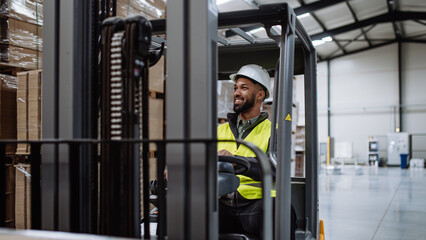 Portrait of warehouse worker driving forklift. Warehouse worker preparing products for shipmennt, delivery, checking stock in warehouse. Banner with copy space.