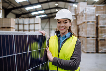 Female worker carrying solar panel in warehouse, factory. Solar panel manufacturer, solar...