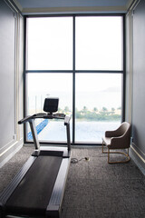 Treadmill running machine in modern contemporary fitness with swimming pool and window ocean view tropical trees mountain range background in luxury hotel Nha Trang, Vietnam, indoor gym - obrazy, fototapety, plakaty