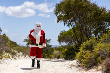 Santa is coming walking towards us through bushland with his sack over his shoulder
