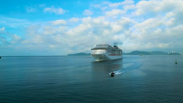 Cruise liner sailing. People on the upper deck celebrates vacation. 4K aerial view of shipboard of the cruise ship leaving terminal. Water transportation.
