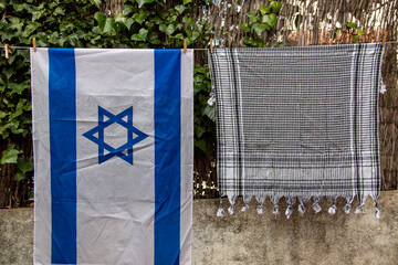 Israel flag and Palestinian scarf together lying on a rope to dry after washing or lying on a...