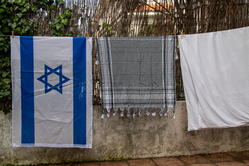 Israel flag and Palestinian scarf together lying on a rope to dry after washing or lying on a...
