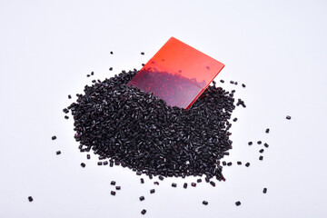 Transparent red masterbatch granules with color chips, isolated on a white background, this polymer...