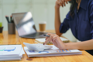 Close-up portrait of businesswoman accountant using calculator and laptop for matching financial data saving in office room, Business financial, tax, accounting concept.
