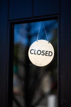 Closed sign hanging in glass pane of shop front door
