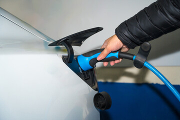 Detail of a man's hand with the electric car charger, in a charger in a shopping center