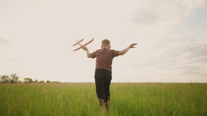 a little boy running in the park on the grass with a toy airplane in his hands. happy family...