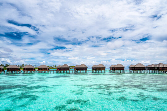 Scenic view of water villas in Maldives with turquoise pristine water and dramatic storm sky 