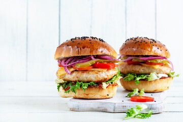 Chicken hamburger. Sandwich with chicken burger, tomatoes, cheese, pickled cucumber and lettuce. Cheeseburger.