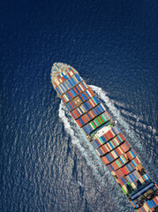 Aerial top down view of a large container cargo ship in motion over open ocean as a concept for...