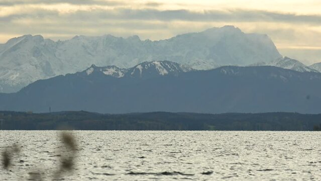 Snowy Alps behind Starnberg lake in a yellow cloudyb autumn evening near Munich