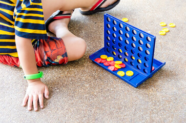 young boy is sitting on the floor, focused and engaged, playing connect game.