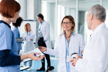 Fototapeta premium Group of doctors talking during conference, discussing research findings. Medical networking. Medical experts attending an education event, seminar in board room.