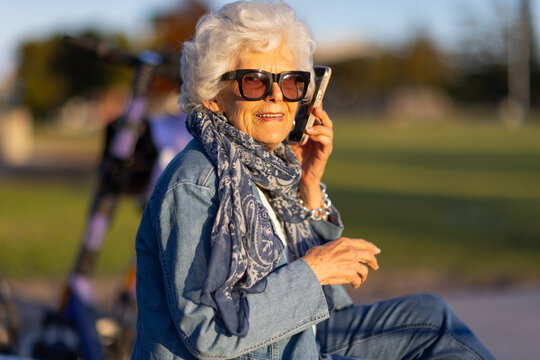 elderly lady dressed in denim outside in a park with phone to her ear