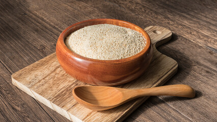 cassava flour in wooden dish and wooden spoon on cutting board on the  wooden table
