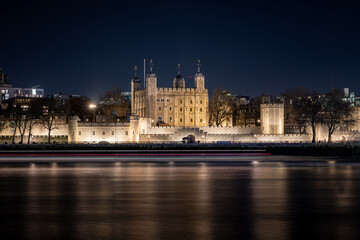 Obraz premium A general view of The Tower of London at night time with light reflections on the Thames river. Long exposure night photography.