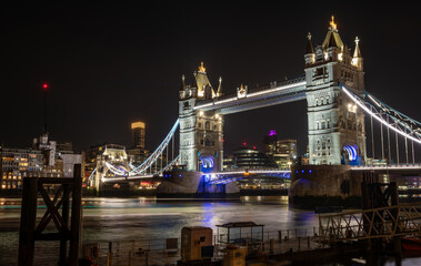 Fototapeta na wymiar A night time, long exposure view of Tower Bridge from the north side of the Thames river with beautiful light reflections on the water.
