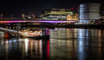 Fototapeta na wymiar A night time view of London Bridge with colourful reflections on the water of the Thames River.