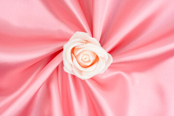 Pink satin fabric texture background with rose flower is center position.