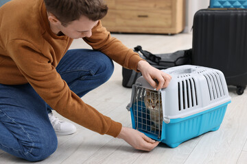 Travel with pet. Man closing carrier with cat at home