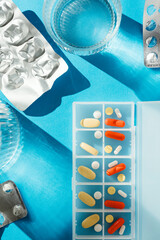 Daily treatment with tablet and capsule pills on blue background
