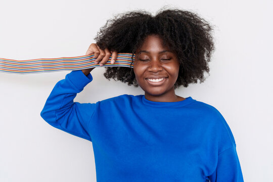 Young Afro woman holding cables near head against white background