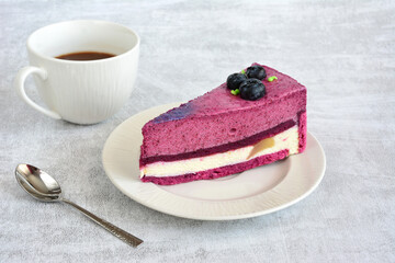 slice of layered blueberry cake on the saucer decorated with blueberry 
